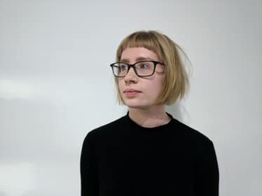 woman wearing glasses with short blonde hair with fringe