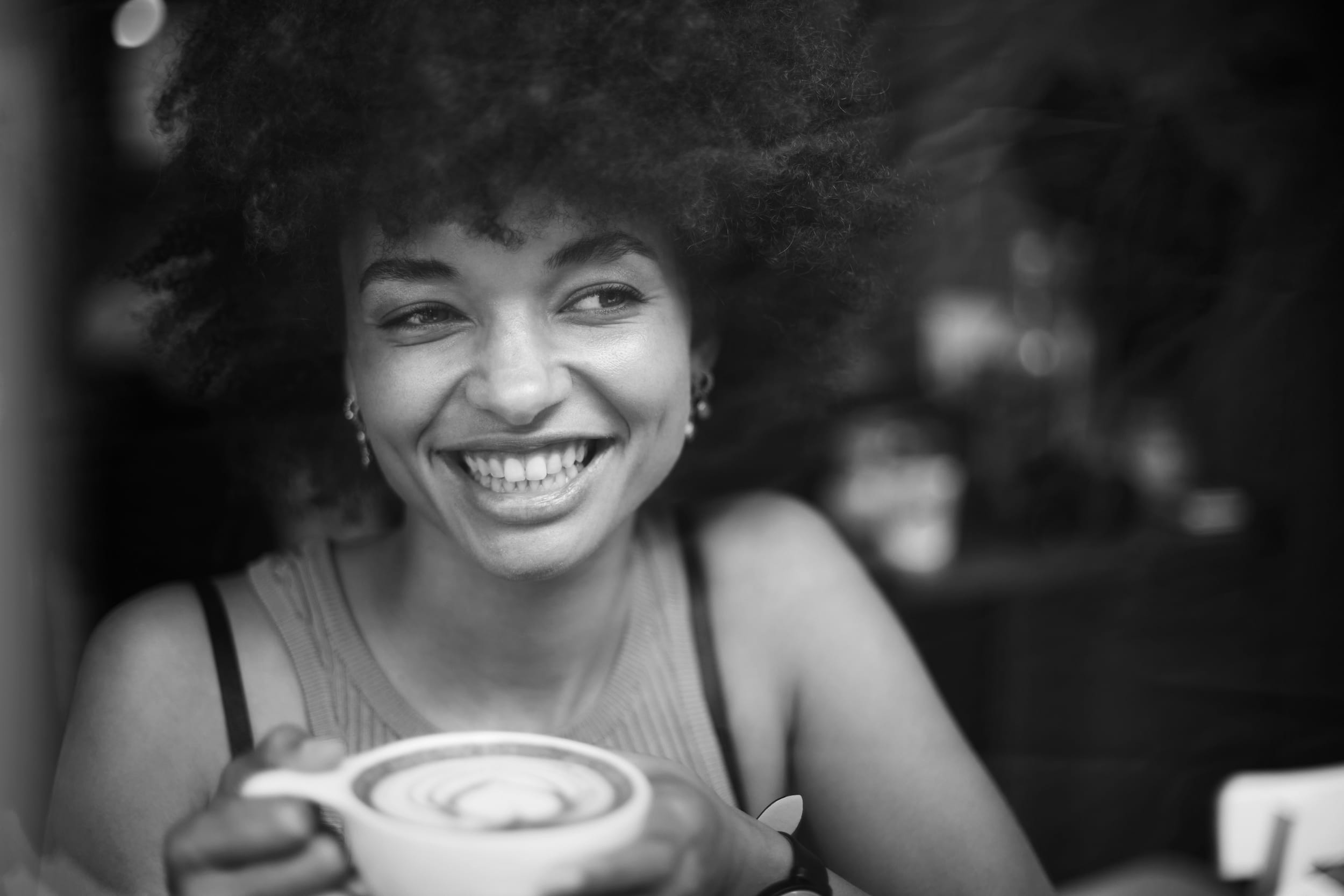 Smiling woman holding coffee cup in cafe window