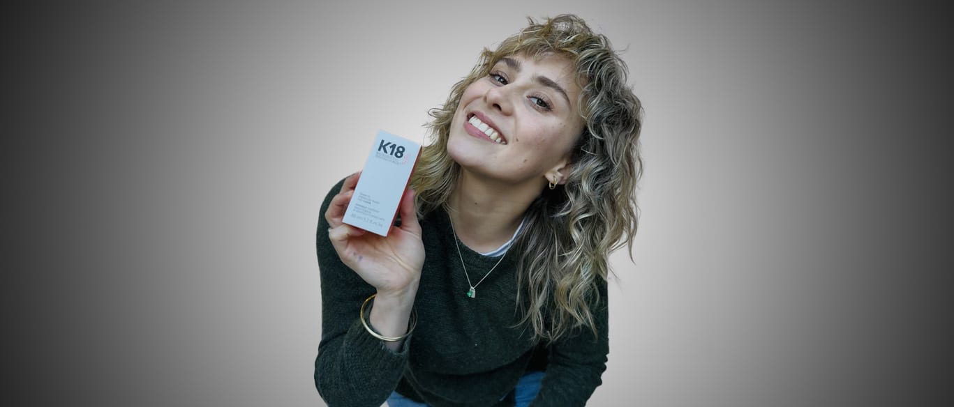 Person smiling holding K18 hair product